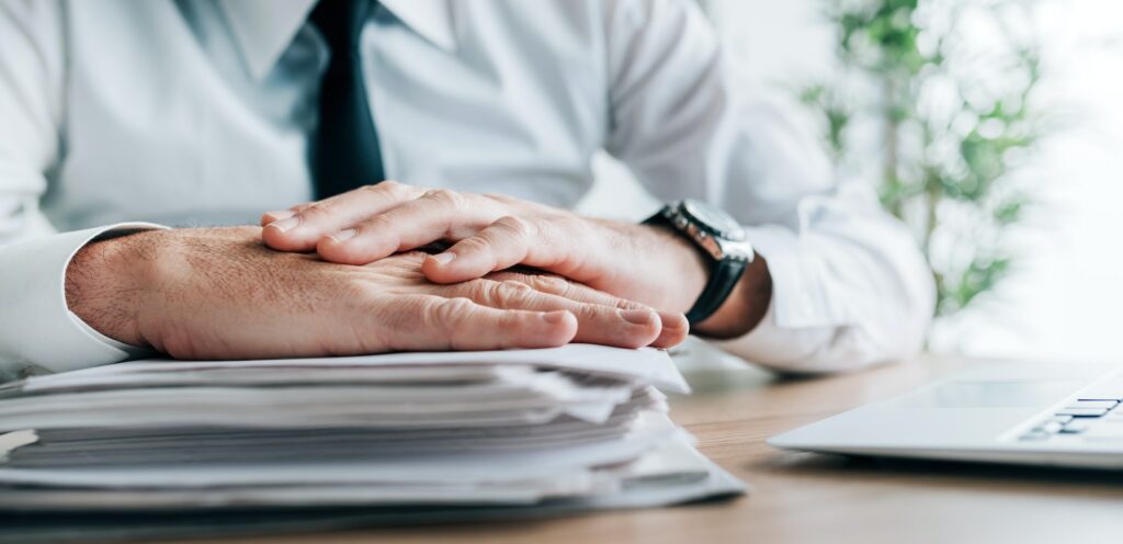 Insurance agent with stack of policy contracts on office desk